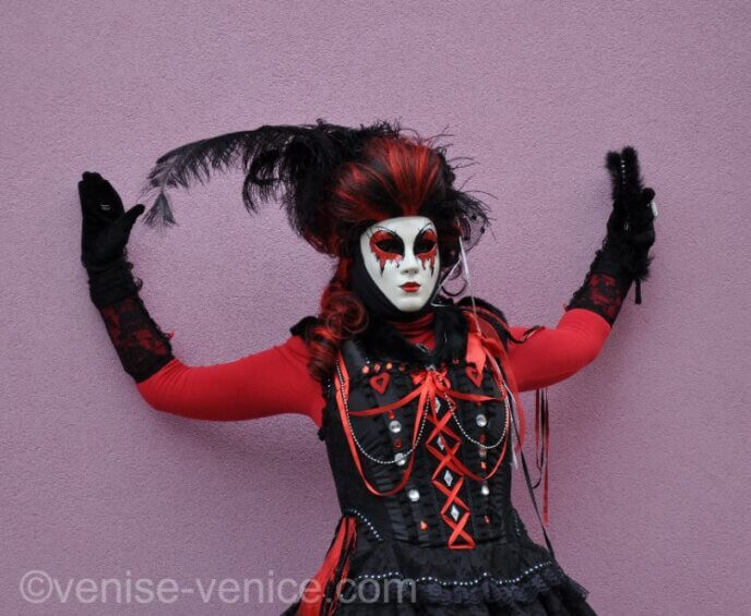 Une personne déguisée pose contre un mur à Burano pendant le carnaval de Venise